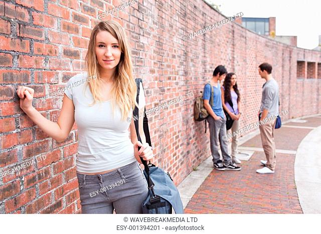 Cute student posing while her friends are talking outside a building