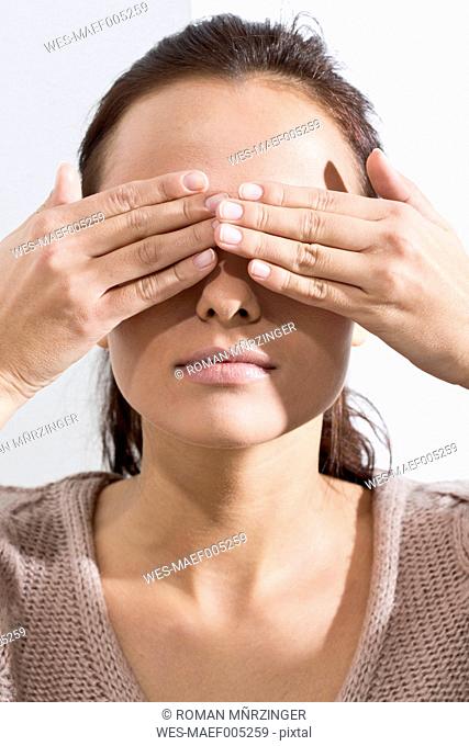 Portrait of young woman covering eyes