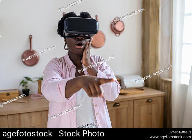 Virtual reality. African woman in pink clothes in vr glasses looking excited