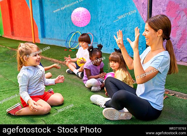 Kinder beim Ball spielen zusammen mit der Turnlehrerin im internationalen Kindergarten