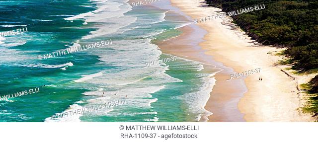 Panoramic photo of surfers heading out to surf on Tallow Beach at Cape Byron Bay, New South Wales, Australia, Pacific