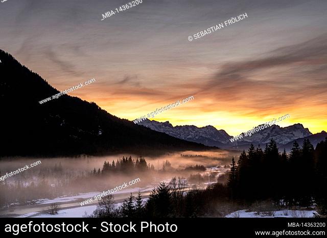 The Isar winds through the landscape covered with hoarfrost and partly snowy in winter. In the background the Zugspitze and a fantastic evening glow over the...