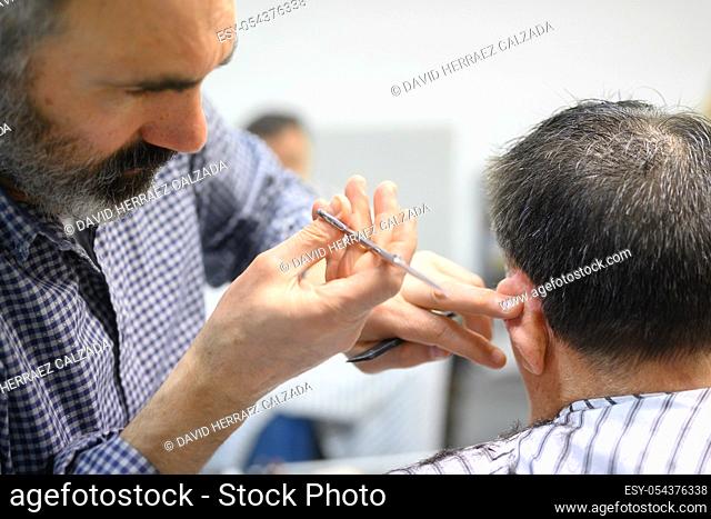 Barber trimming hair of old man at barber shop