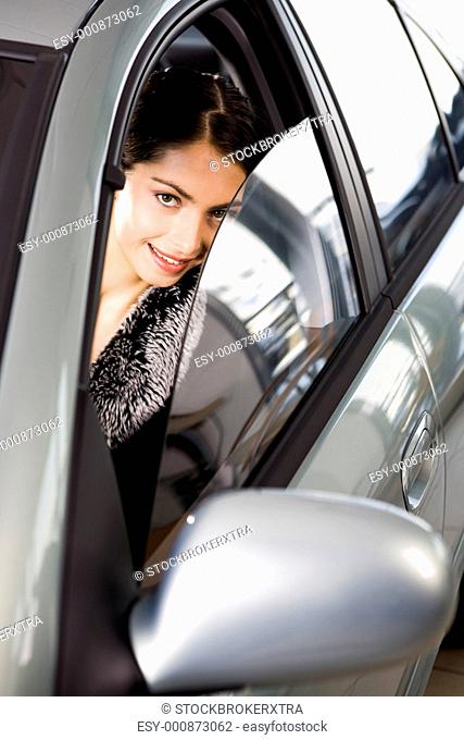 Portrait of vivid brunette looking with interest through the window of her car