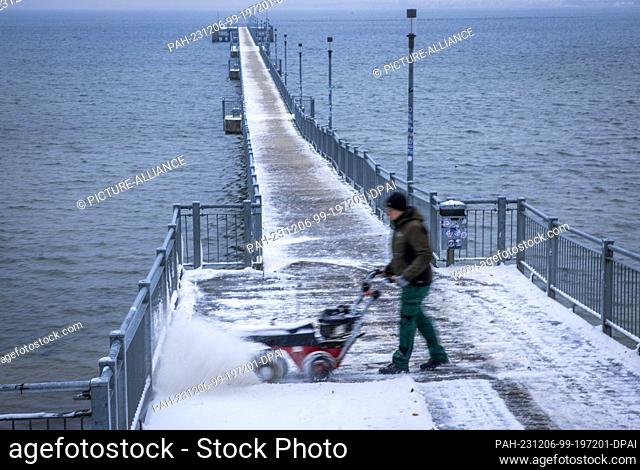 05 December 2023, Mecklenburg-Western Pomerania, Wismar: A footpath at the pier is cleared of snow with a special sweeper