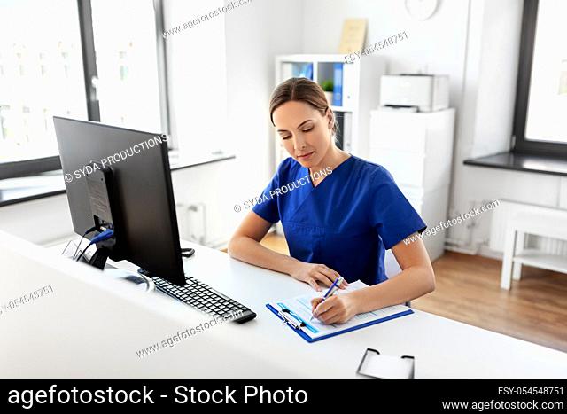 doctor or nurse with clipboard working at hospital