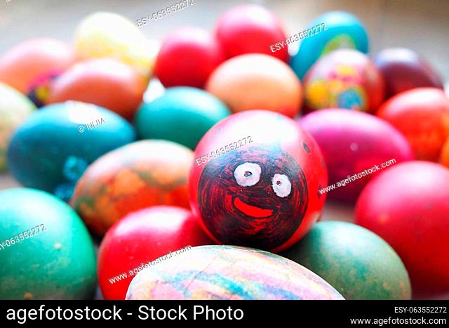 Easter egg - ladybug. An egg painted red and black with a cheerful face. Easter colorful eggs. Boiled chicken dyed eggs with red, pink, blue, green, yellow