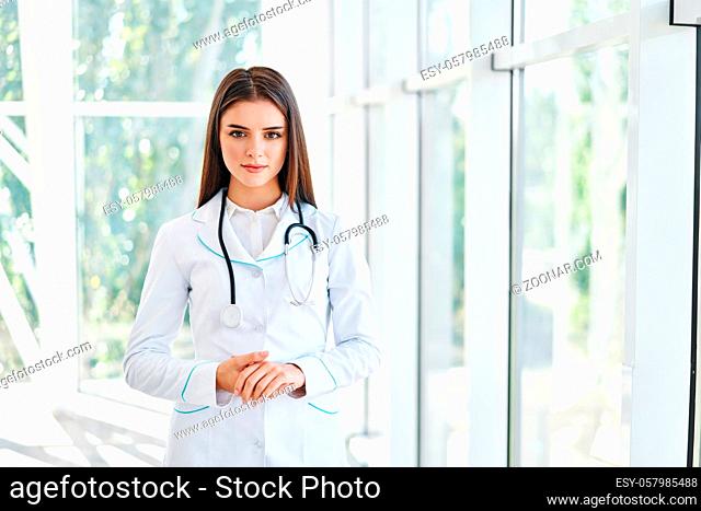 Confident doctor looking at camera in hospital background. Medicine, profession and healthcare concept