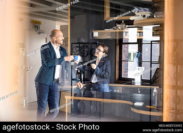 Smiling business people toasting coffee cup while standing at office