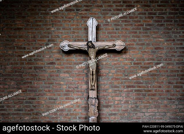 06 August 2022, North Rhine-Westphalia, Dormagen: A cross can be seen in front of a brick wall in a church. Photo: Silas Stein/dpa