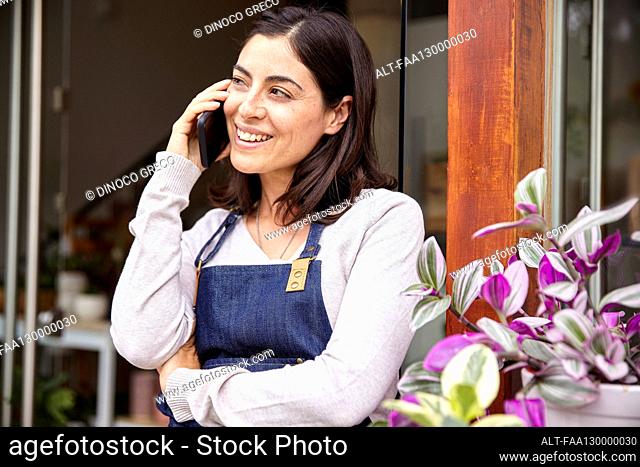 Female entrepreneur talking on smart phone while standing in garden center