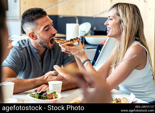 Blond businesswoman feeding pizza to businessman in office
