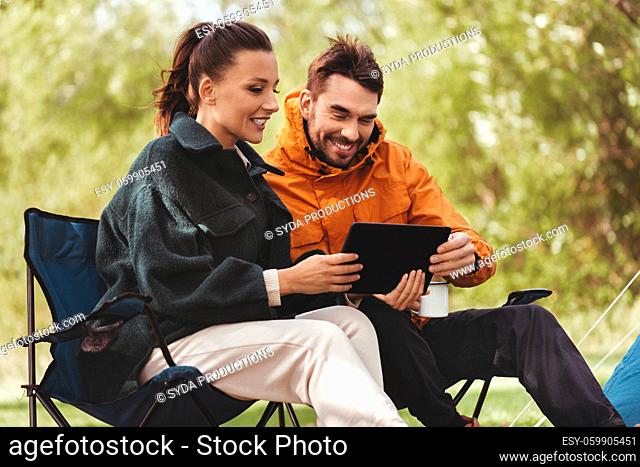 couple with tablet pc drinking tea at tent camp