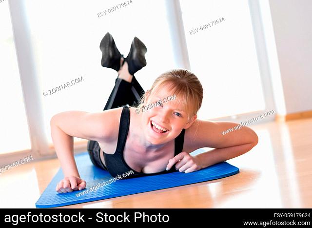 Happy young girl doing pushups exercises on the floor at home
