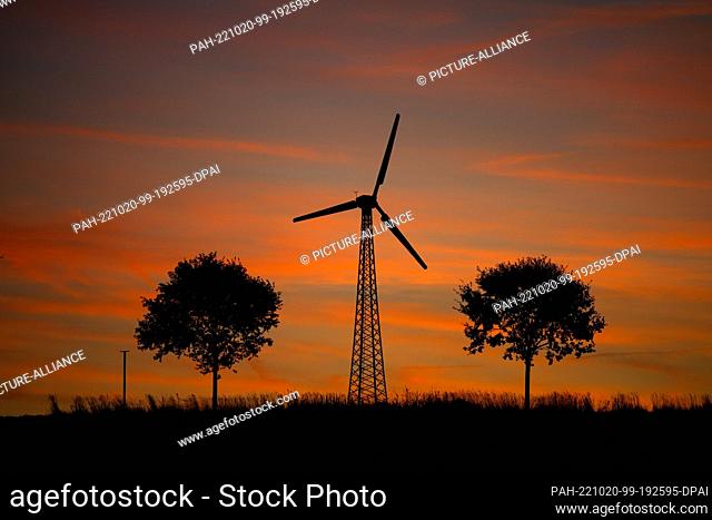 20 October 2022, Lower Saxony, Syke: A wind turbine stands out against the red glowing sky. Today, from the west, dense clouds and rain advancing to about the...
