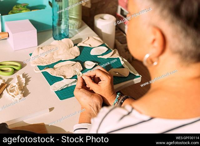 Female artist making clay leaf in workshop