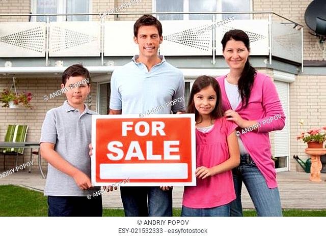 Family selling their home holding for sale sign