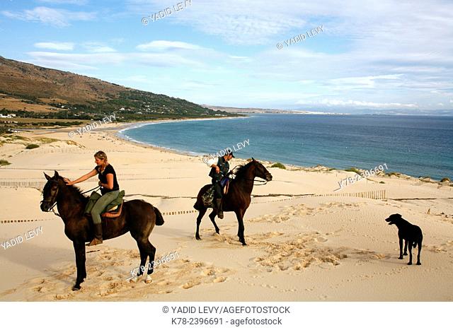 People riding horses on the dune of Ensenada de Valdvaqueros with a view over Playa de los Lances beach, Tarifa, Andalucia, Spain