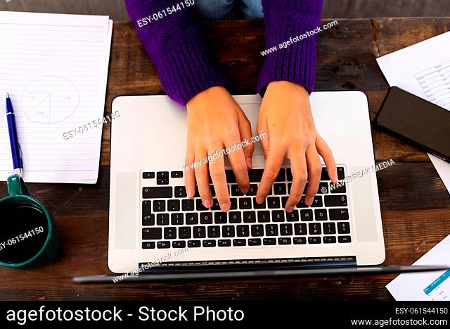 Overhead view of hands of caucasian woman using laptop on coffee table, working from home