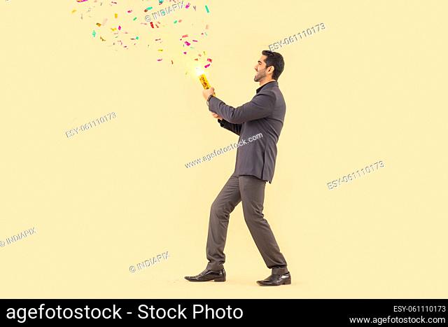 Happy businessman celebrating new year with confetti cracker