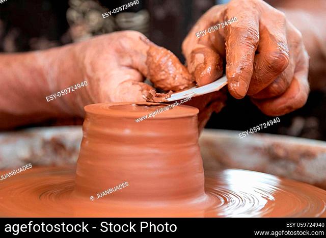 Hands of the potter. The potter makes pottery dishes on potter's wheel. The sculptor in workshop makes clay product closeup