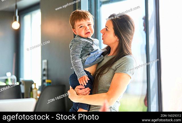 Mutter trägt ihr weinendes Kind zu Hause zum Trösten auf dem Arm