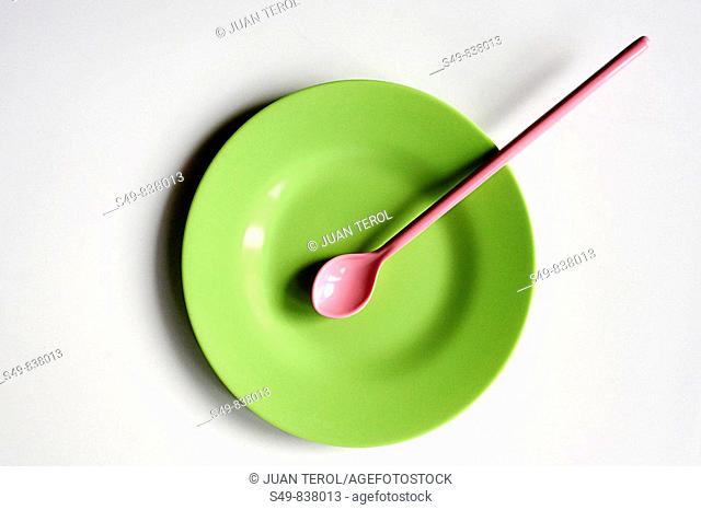 zenithal view of a plastic color plate and spoon on white background