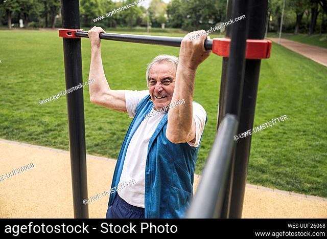 Active senior man exercising on gymnastics bar at park