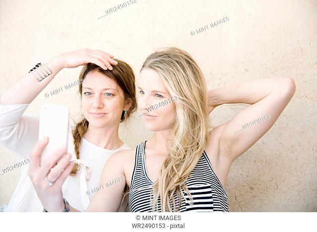 Two smiling women taking a selfie with a cell phone