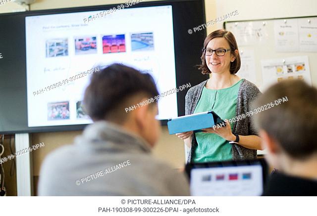 07 March 2019, Lower Saxony, Gehrden: A teacher stands with an iPad in front of a digital blackboard in the English class of a 5th class at the secondary school...