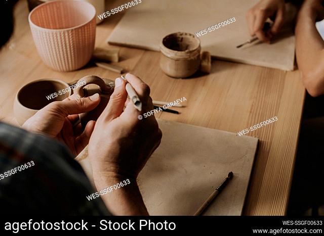 Young man curving cup with tool in workshop
