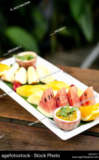 mixed fresh cut organic fruit salad platter outdoors on wood table