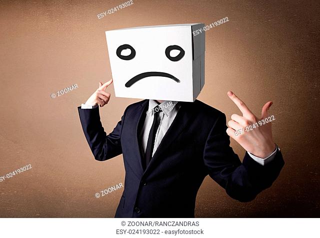 Businessman gesturing with cardboard box on his head with sad face
