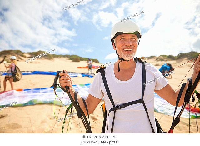 Mature male paraglider on beach with equipment