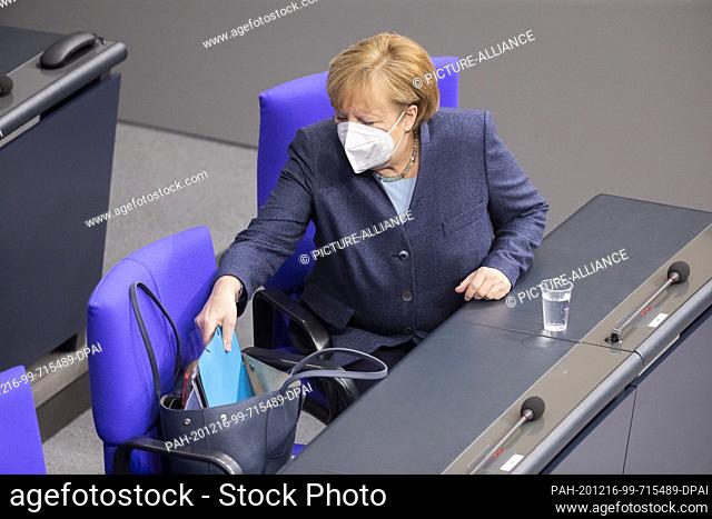 16 December 2020, Berlin: Chancellor Angela Merkel (CDU) reaches into her pocket ahead of the government inquiry in the German Bundestag
