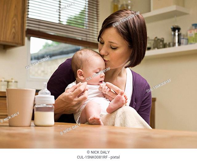 Mother kissing her baby in the kitchen