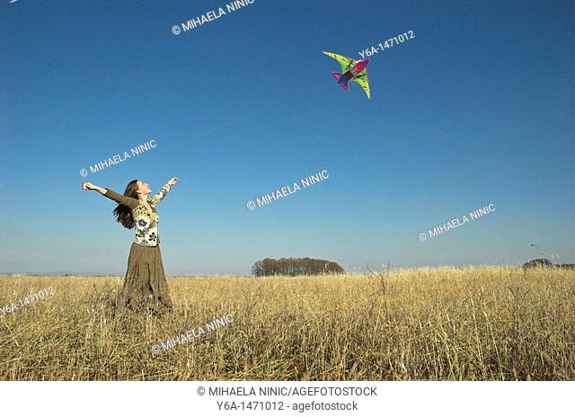 Young woman in field flying kite