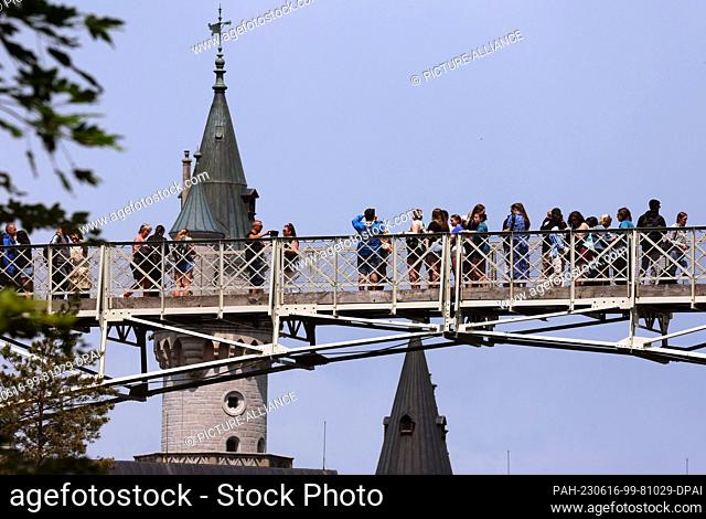 16 June 2023, Bavaria, Schwangau: Tourists stand on the Marienbrücke bridge in front of Neuschwanstein Castle. A man pushed two female tourists into a ravine...