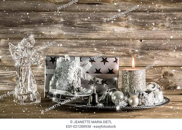 Silver and beige christmas decoration with present, angel and candle on wooden background