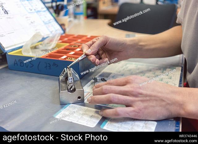 Woman locksmith repairing a lock using tool to measure a part