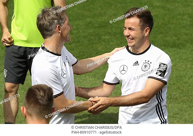 Germany's Bastian Schweinsteiger (L) congratulates teammate Mario Goetze (R) on his birthday during a training session in Ascona, Switzerland, 03 June 2016