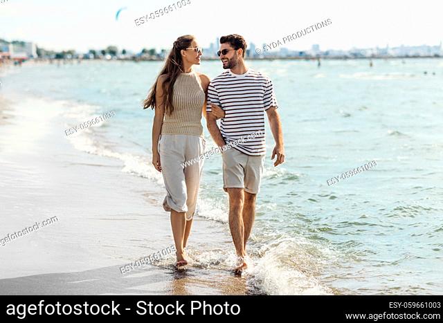happy couple walking along summer beach