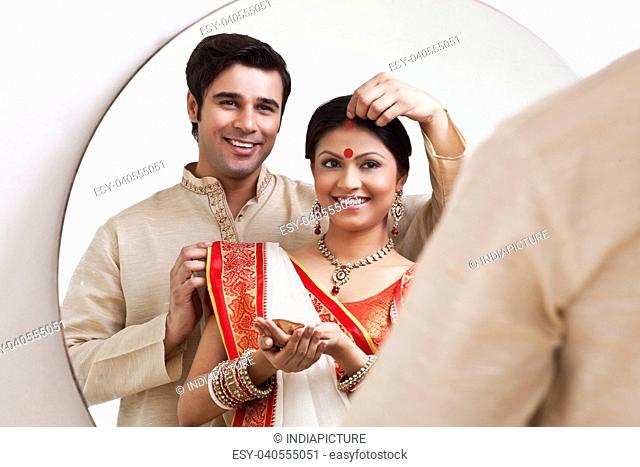 Bengali man putting sindoor on wife's forehead