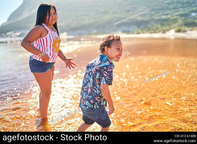 Happy brother and sister playing in sunny ocean surf