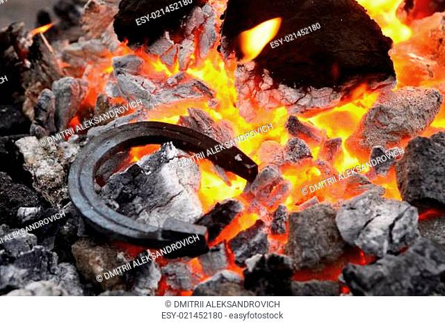 Iron horseshoes lying on hot coals and burning flame