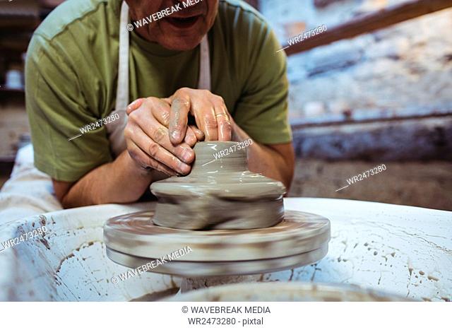 Cropped image of craftsman making ceramic container in pottery workshop