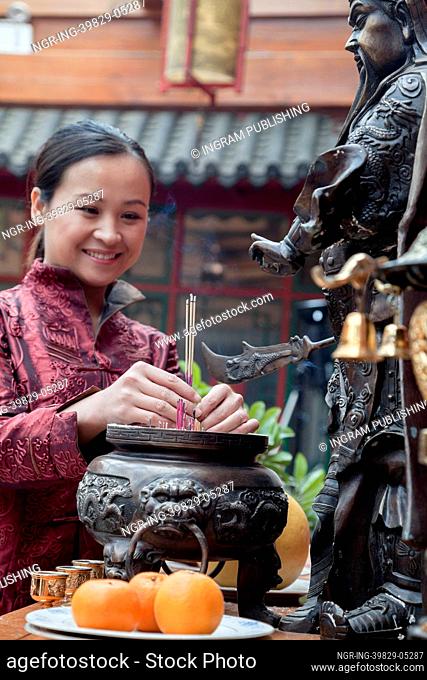 Woman offering incense, temple, Beijing