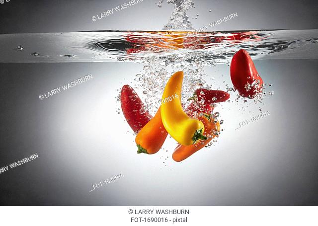 Close-up of red and yellow chili peppers in splashing water