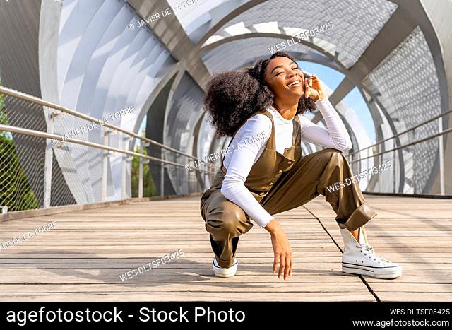 Happy young woman crouching on bridge