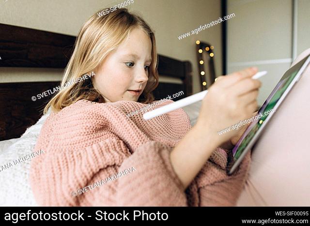 Girl with digitized pen drawing on tablet PC at home